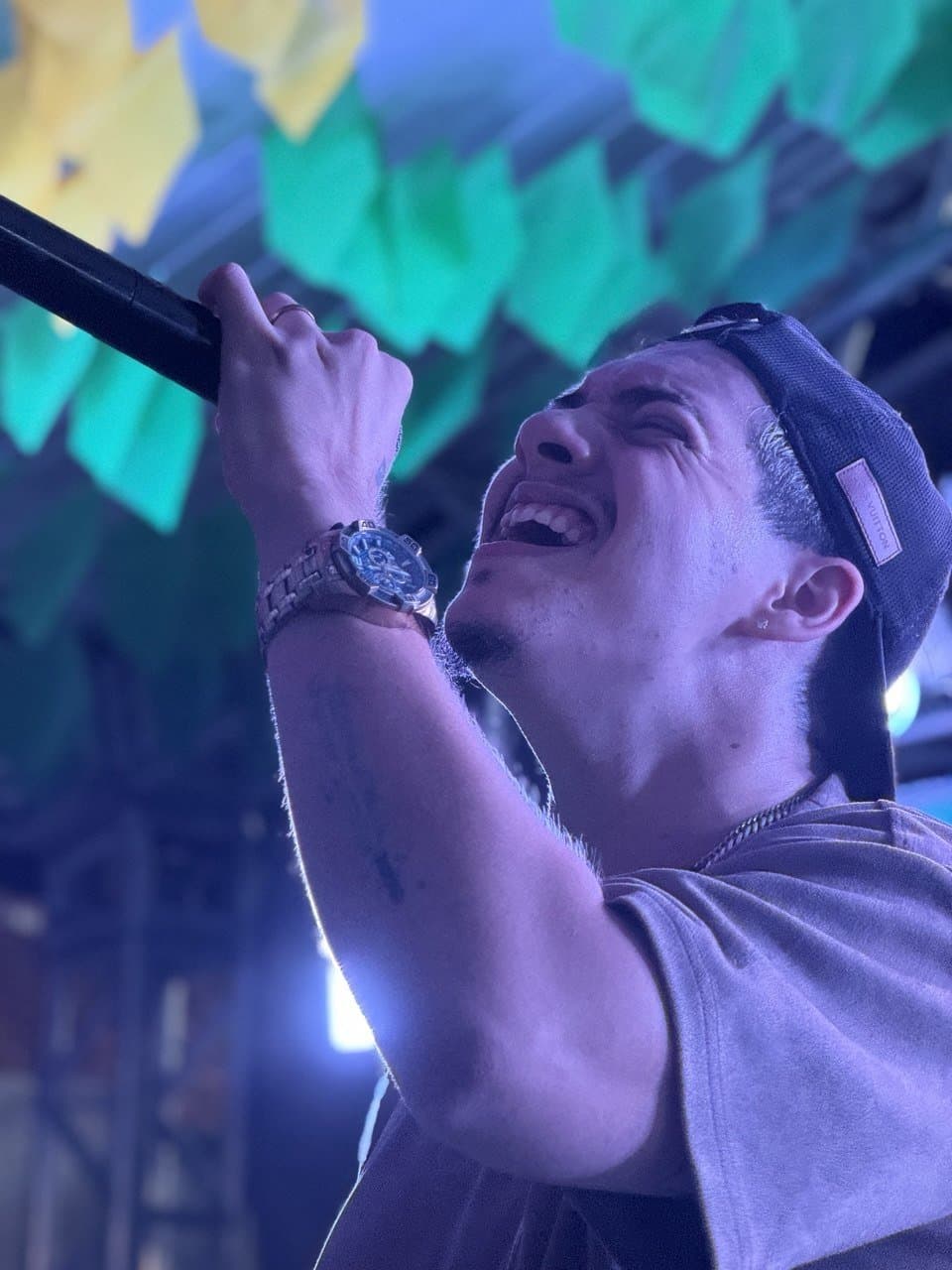 Felipe Stan cantando no palco com luzes coloridas
