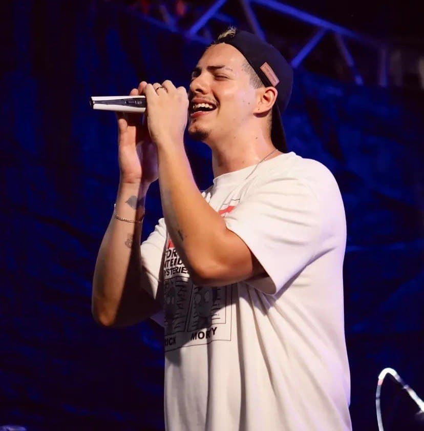 Felipe Stan de perfil cantando sob luz azul de palco